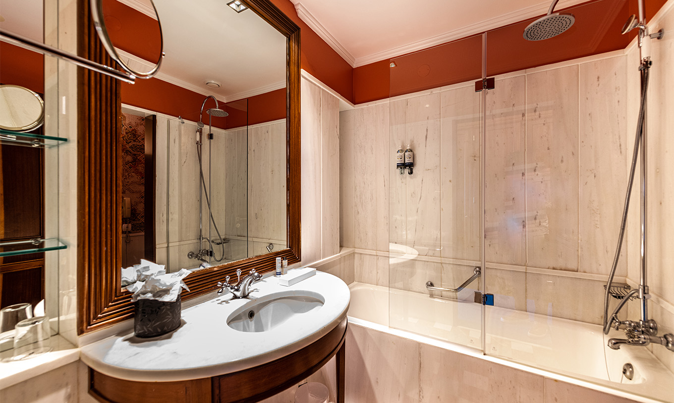 Le Premium Garden du Pestana Palace Lisbonne a une salle de bain avec baignoire et un lavabo en marbre et bois et miroir