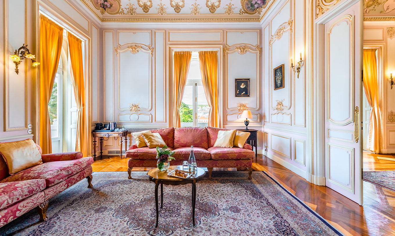La Suite D. Carlos du Pestana Palace Lisbonne a un grand salon luxueux avec deux canapés, tapis et deux fenêtres