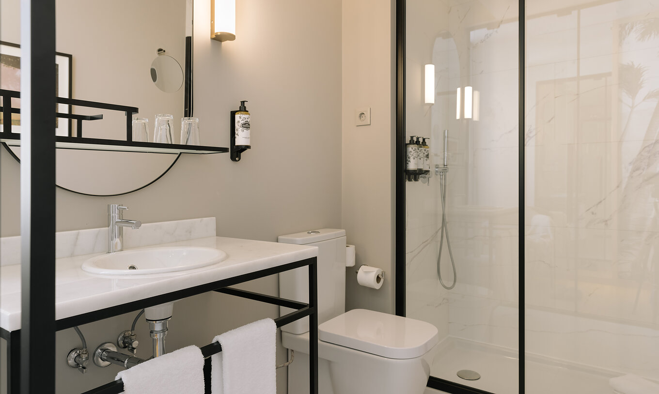 Le Premium Corner du Pestana Rua Augusta Lisboa a une salle de bain avec lavabo avec miroir, serviettes, toilettes et douche