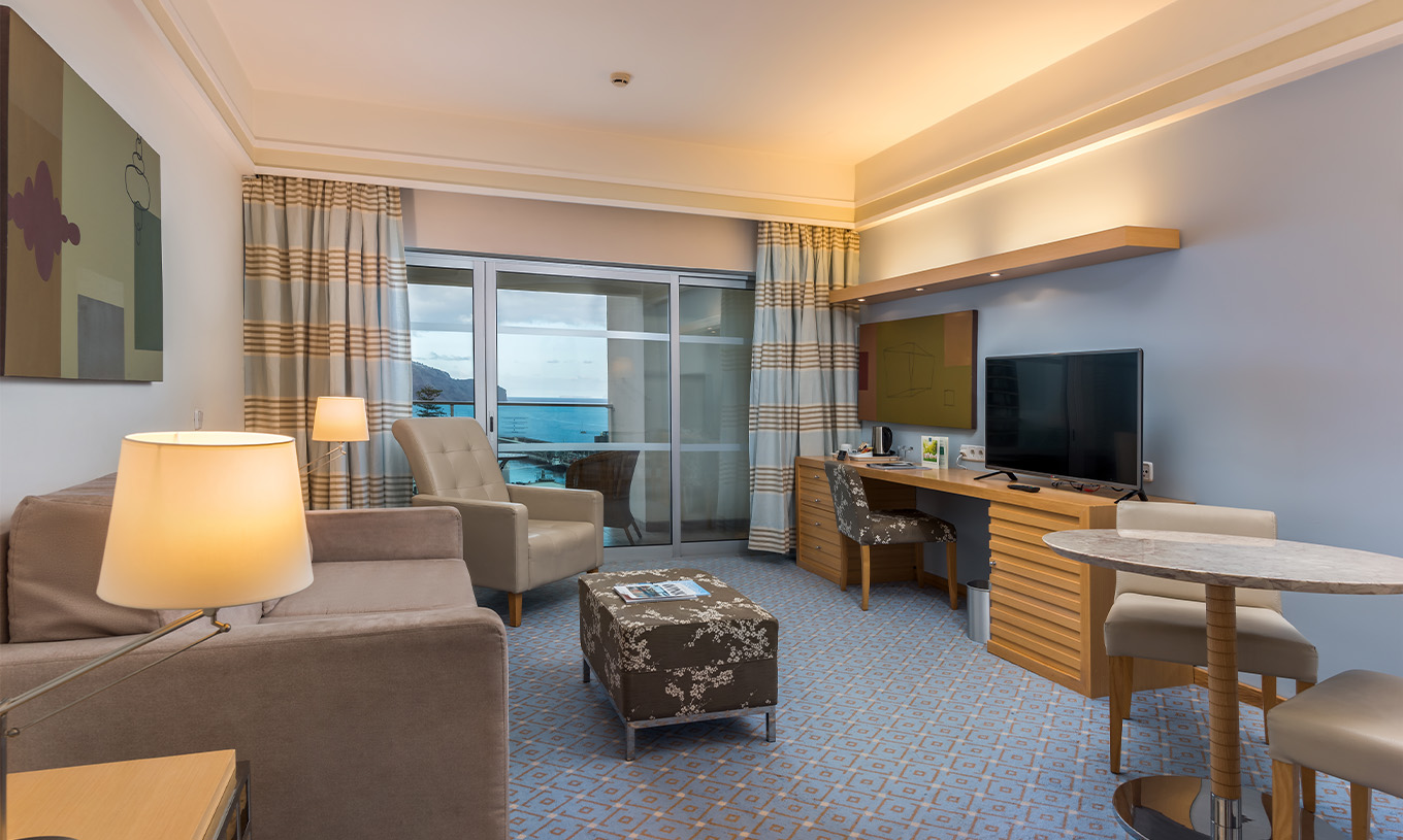Le Double Classique Vue Mer Supérieur du Pestana Carlton Madeira a un coin salon avec canapé, télévision et un balcon