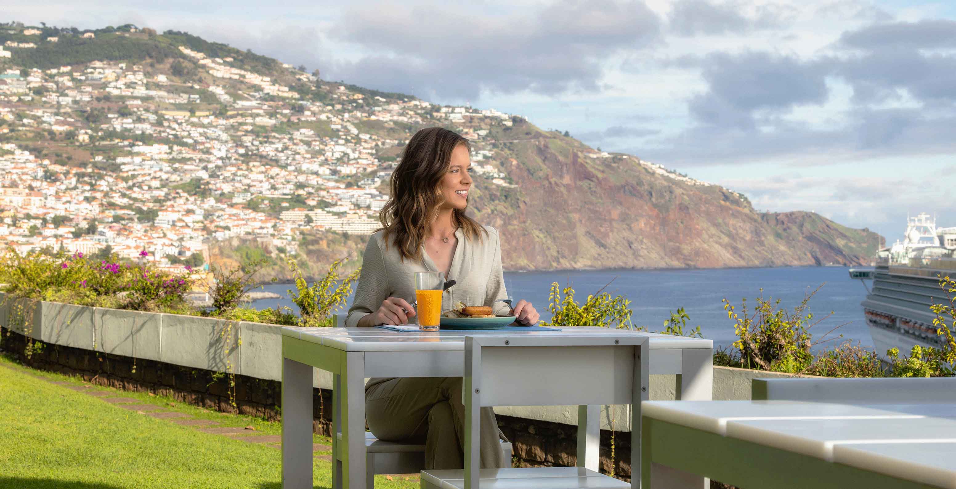 Vue d'une terrasse avec table et chaises longues donnant sur la mer au Pestana Casino Park