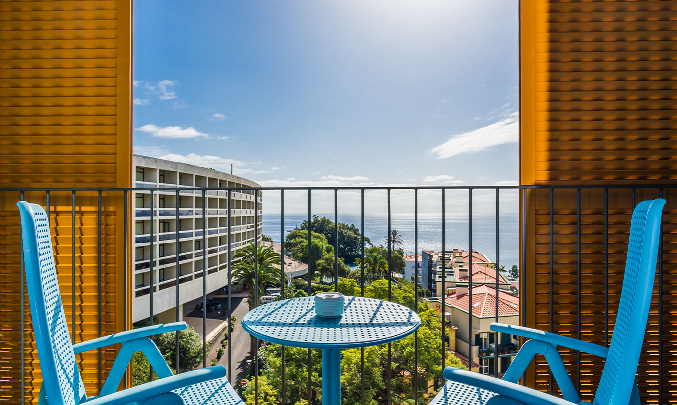 L'Appartement Deluxe Vue Mer du Pestana Casino Studios a un balcon avec vue sur la ville et une table avec chaises bleues