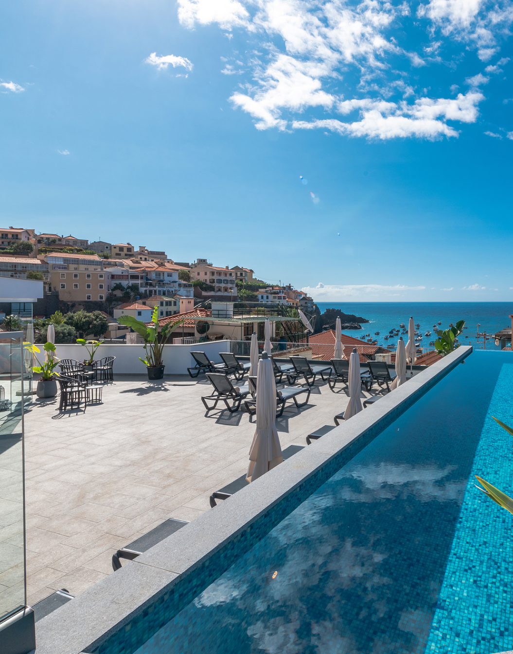 Vue de la piscine extérieure et de la terrasse de l'hôtel à Câmara de Lobos, Madère, avec la mer et la ville en arrière-plan