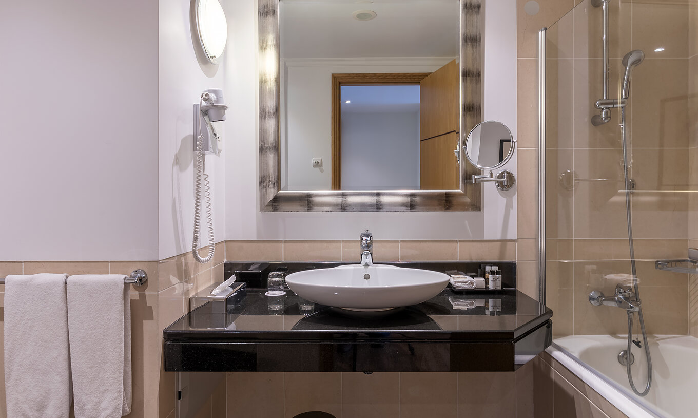La Chambre Classique Vue Mer du Pestana Grand a une salle de bain avec lavabo baignoire avec douche et serviette