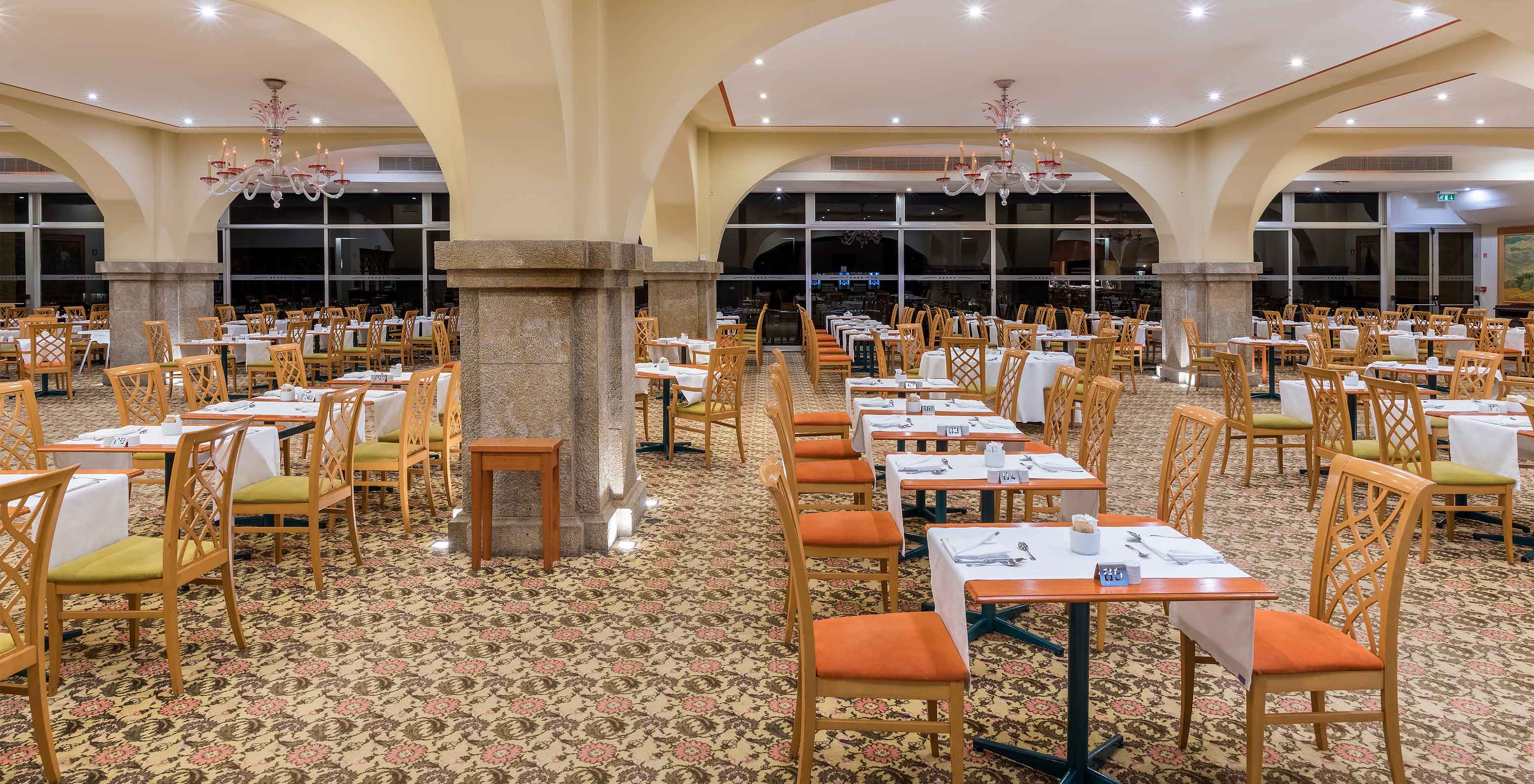 Le restaurant Arcos, à l'Hôtel au Centre de Funchal, à Madère, a une moquette et plusieurs tables et chaises