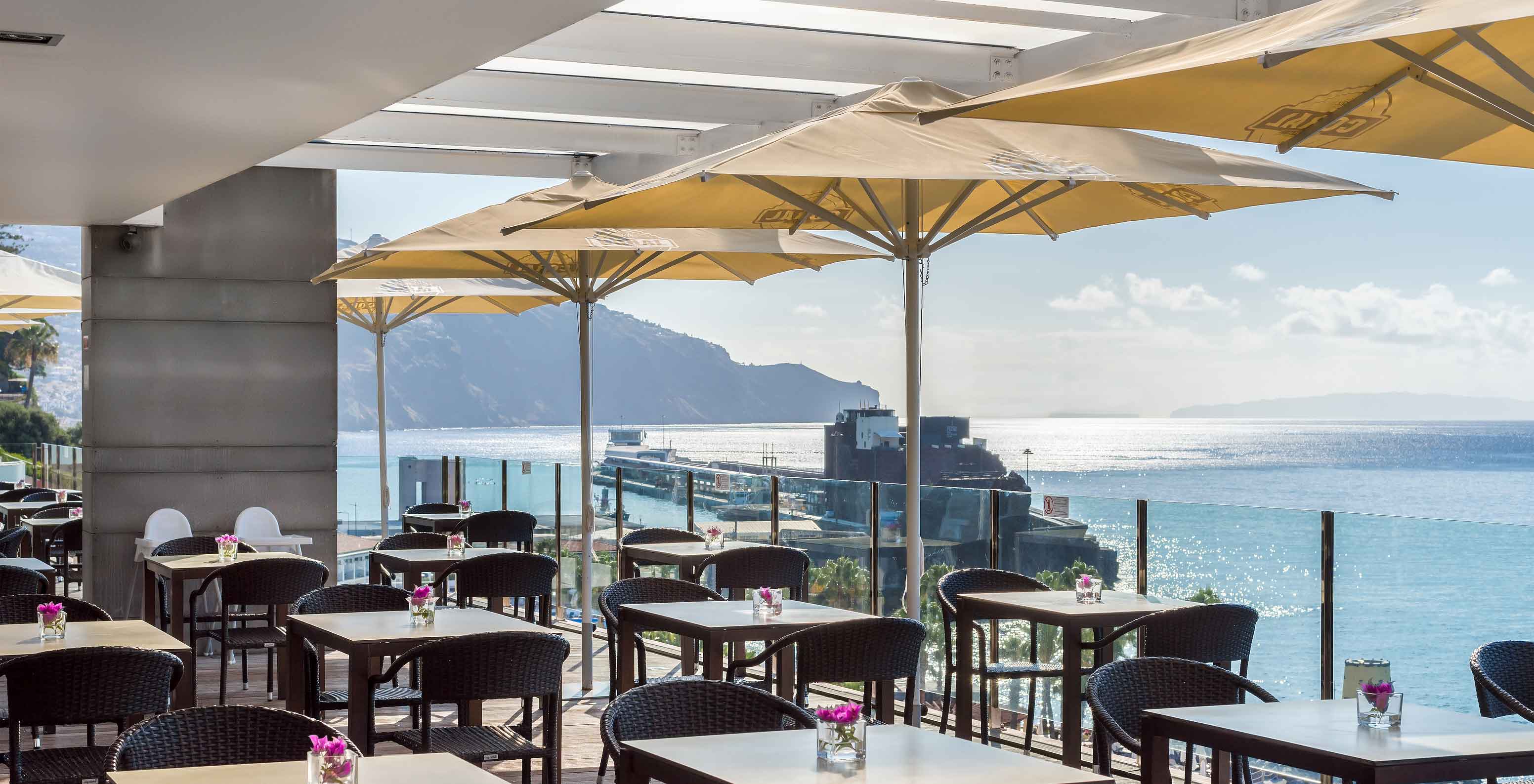Le Pool Bar, à l'Hôtel au Centre de Funchal, à Madère, a plusieurs tables avec vue sur la mer