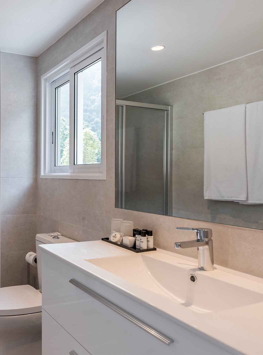 L'Étude - Vue mer du Pestana Quinta do Arco a salle de bain avec douche, toilettes, lavabo avec grand miroir et fenêtre