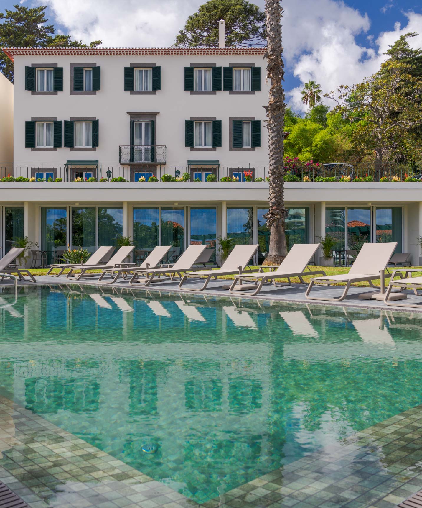 Vue de la piscine extérieure du Pestana Quinta Perestrello, un Hôtel de Charme à Madère, avec le bâtiment derrière