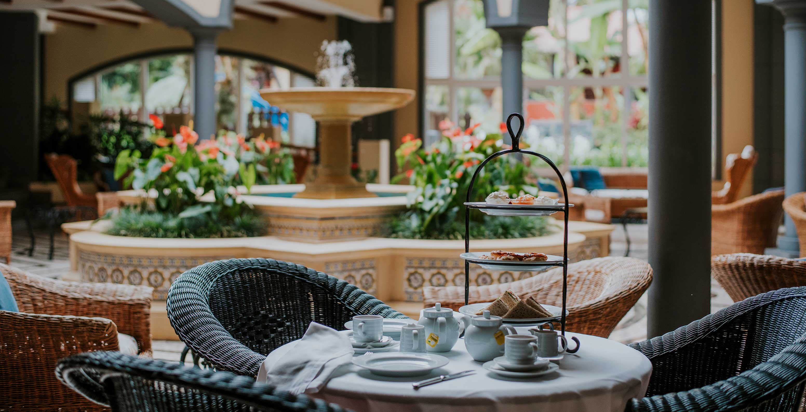 Le bar A Fonte, de l'Hôtel de Charme à Madère a une fontaine avec de l'eau et des fleurs et une table avec des chaises