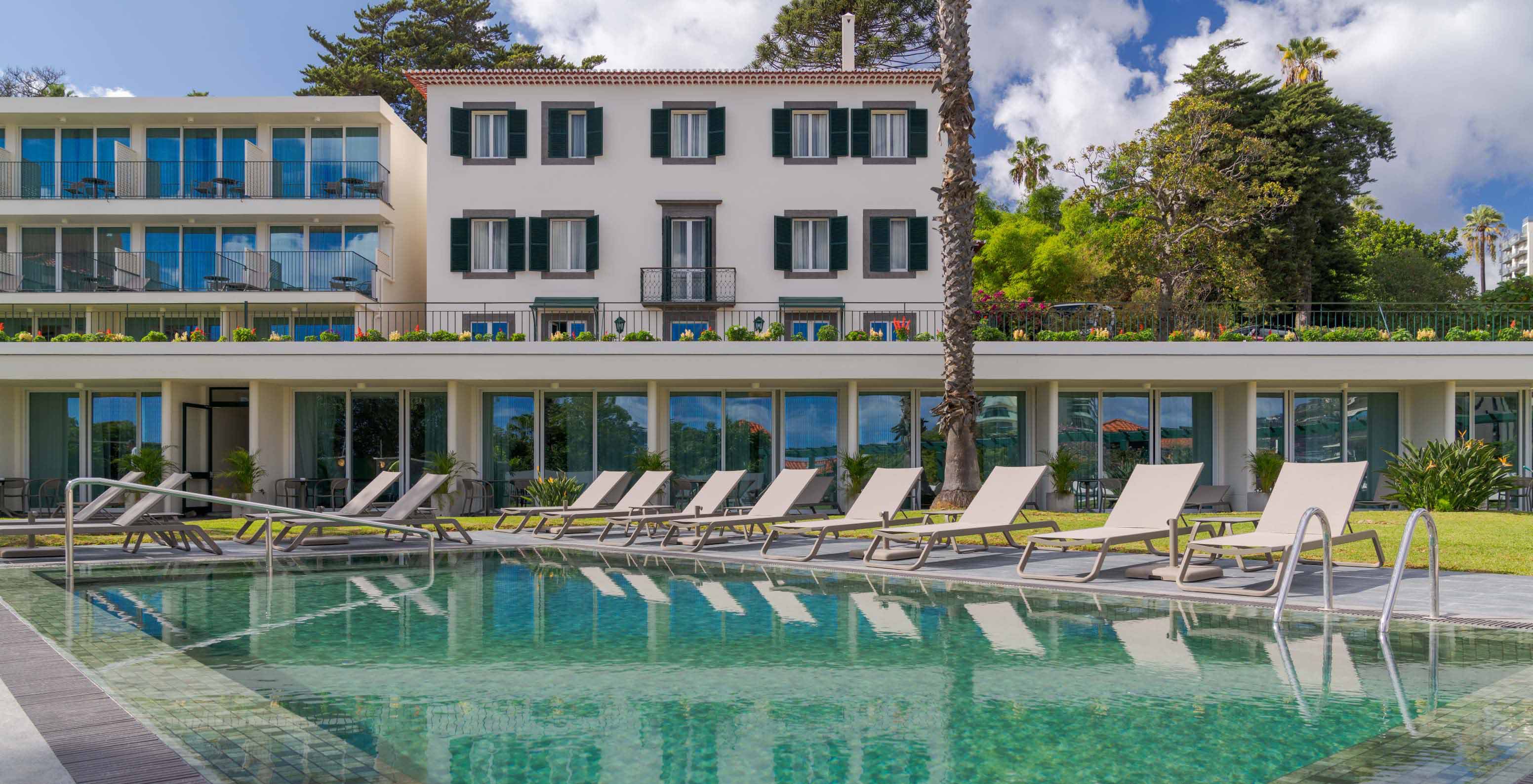 Vue de la piscine extérieure du Pestana Quinta Perestrello, un Hôtel de Charme à Madère, avec le bâtiment derrière
