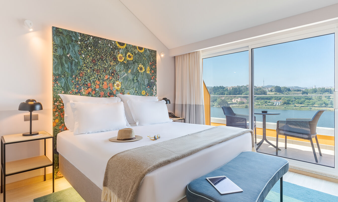 La Junior Suite du Pestana Douro Riverside a un lit double, une table de nuit avec lampe et un balcon avec vue