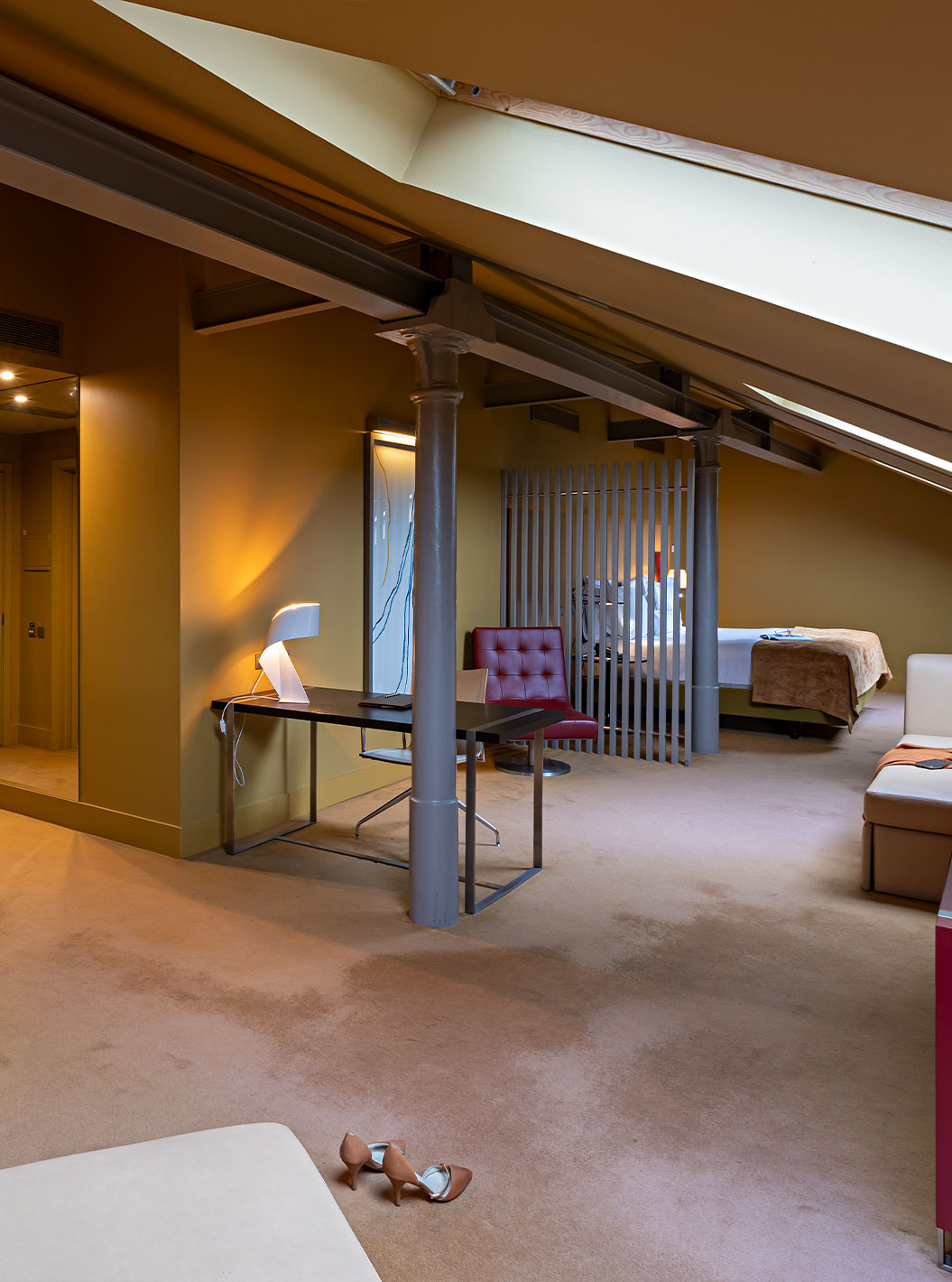 Le Loft Attique du Pestana Palácio do Freixo possède un canapé en cuir beige, un bureau et une armoire rouge