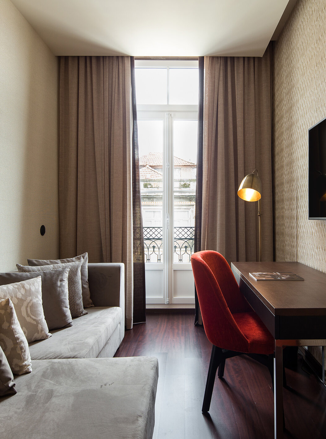 Suite Junior Reserve du Pestana Porto - A Brasileira avec canapé gris, bureau en bois et grande fenêtre