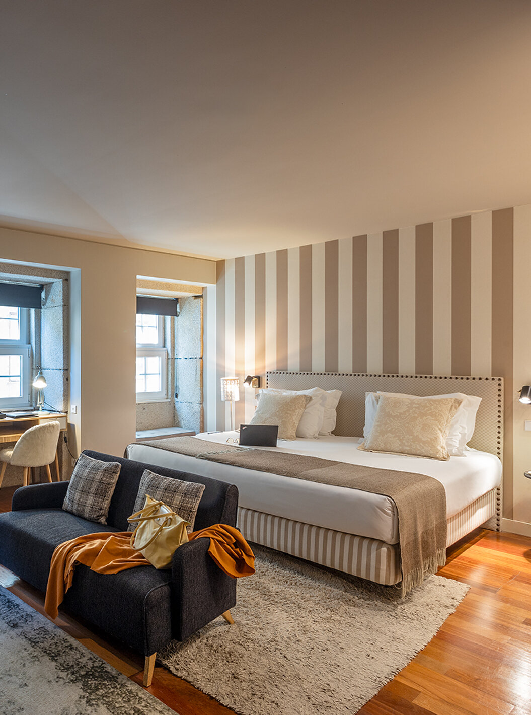 La Heritage Suite du Pestana Vintage Porto dispose d'un lit double, de deux canapés sur des tapis et de plusieurs fenêtres