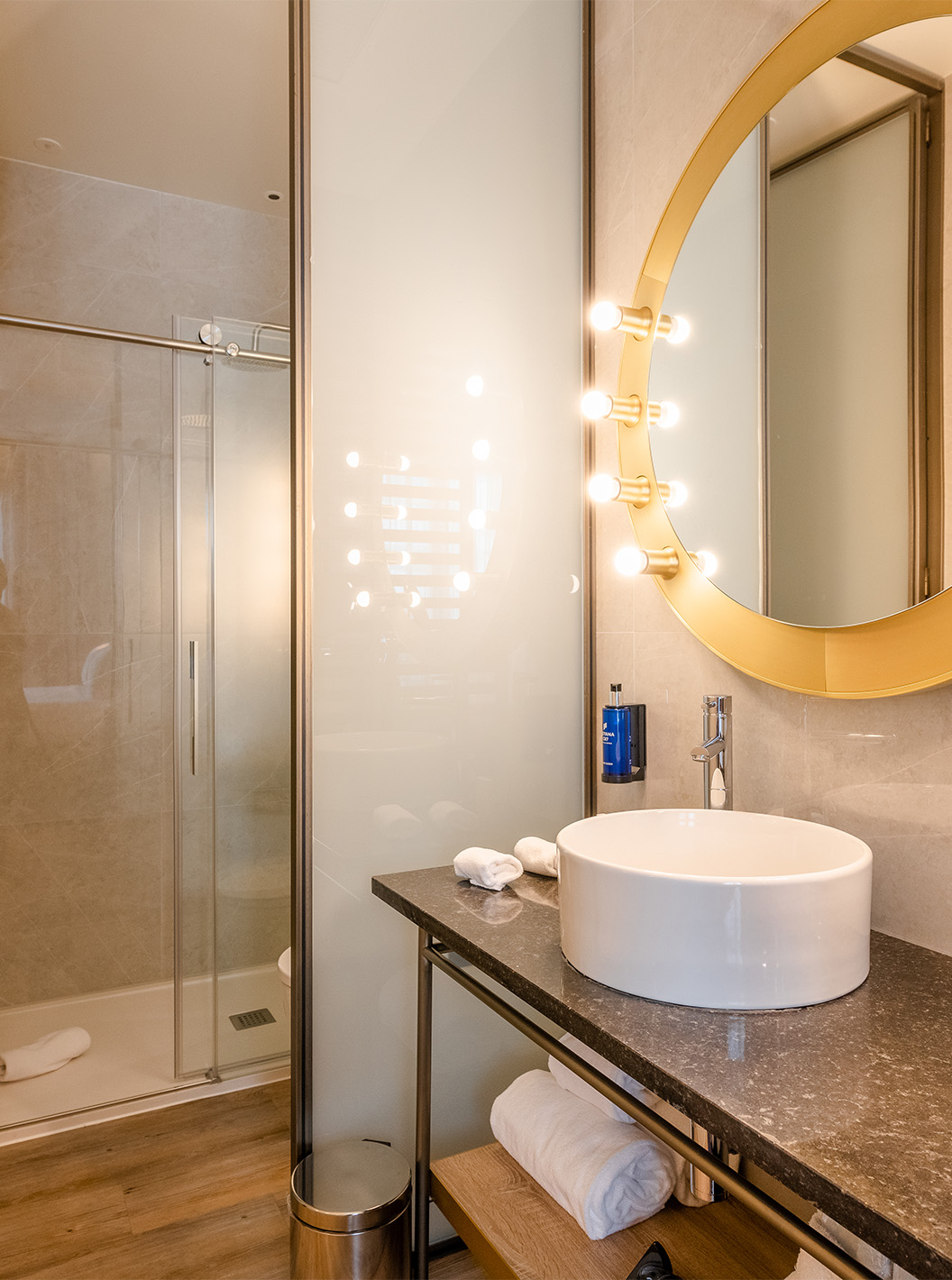 Le Premium avec Vue du Pestana CR7 Gran Vía Madrid a une salle de bain avec miroir rond et douche avec portes coulissantes