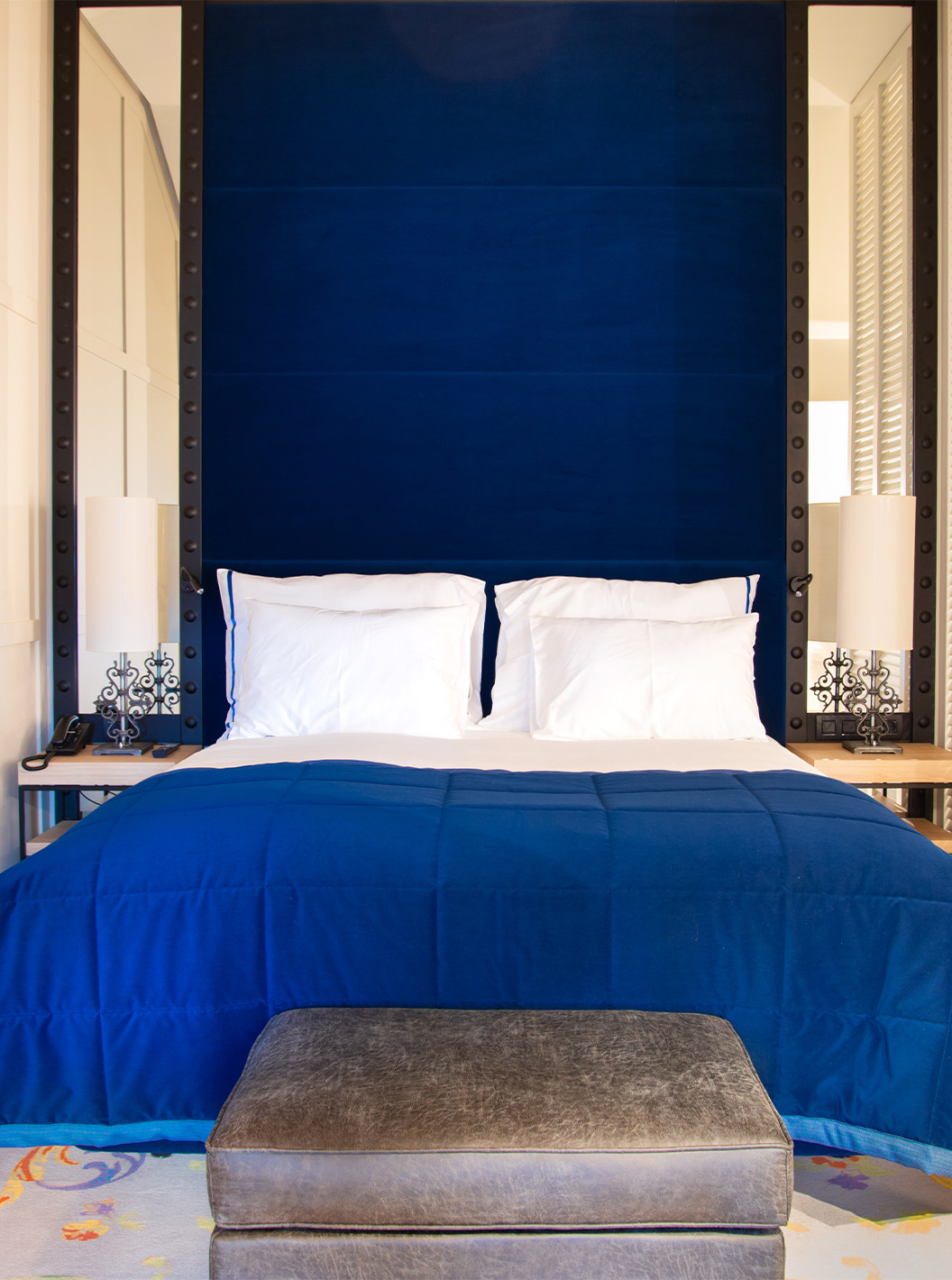 Le Loft du Pestana Plaza Mayor Madrid a un lit double avec une tête de lit bleue et des miroirs, et une télévision au mur