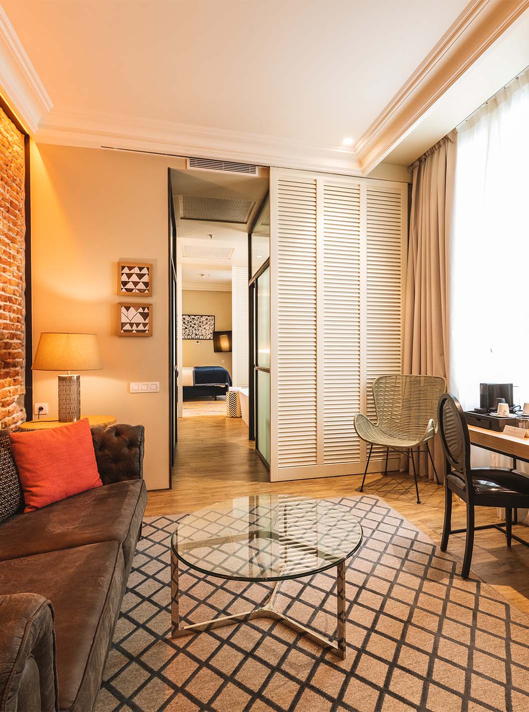 La Suite du Pestana Plaza Mayor Madrid a un salon avec bureau, canapé, télévision et un mur en briques