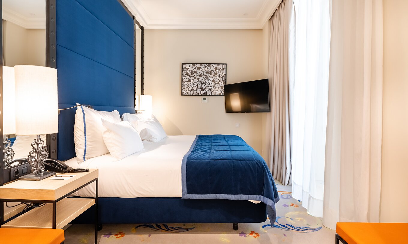 La chambre Supérieure du Pestana Plaza Mayor Madrid a un lit double, une tête de lit bleue, une télévision et des miroirs