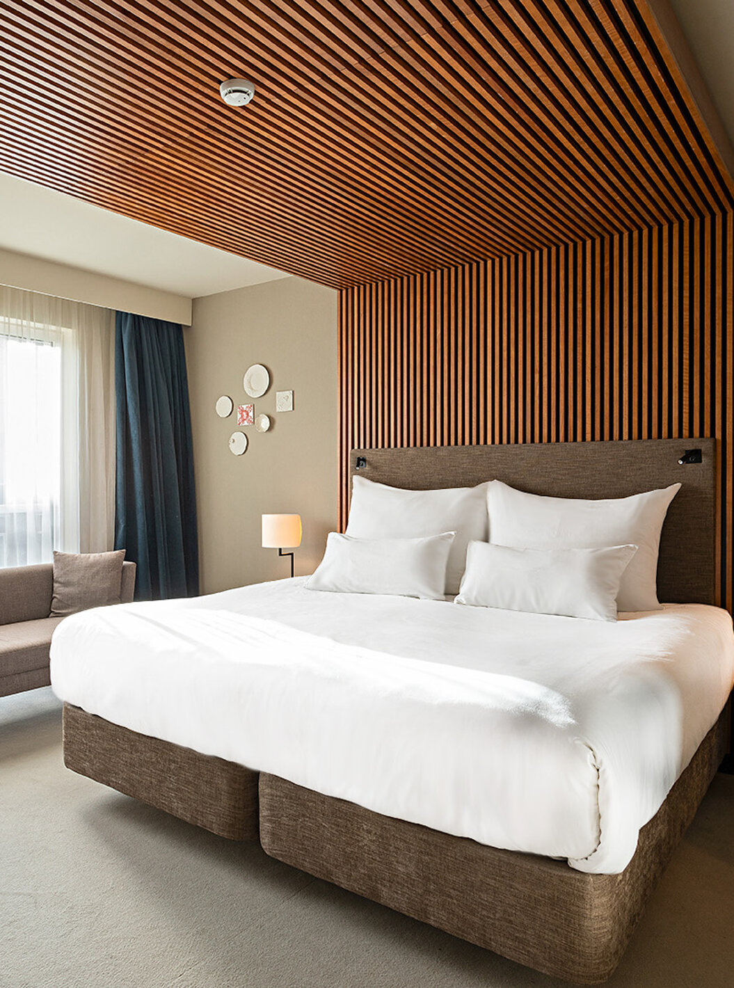 La chambre Executive du Pestana Amsterdam Riverside a un lit double, un canapé, et table de nuit avec lampe