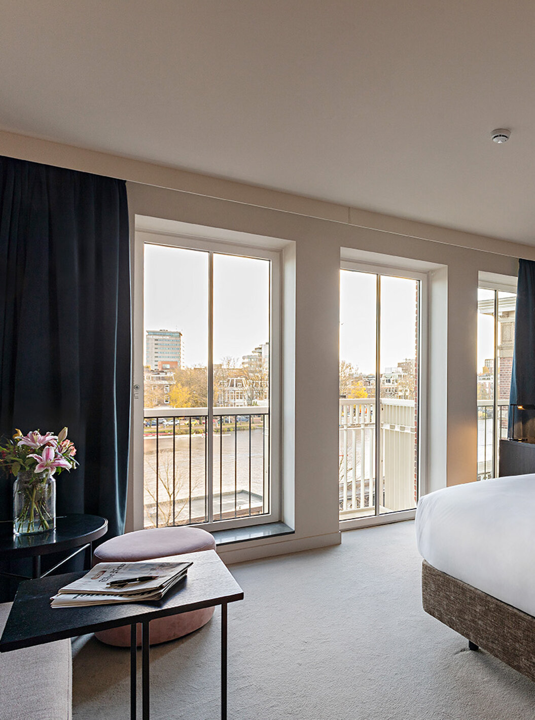 La chambre Premium - Vue Rivière du Pestana Amsterdam Riverside a de grandes fenêtres avec vue sur la rivière, et une table
