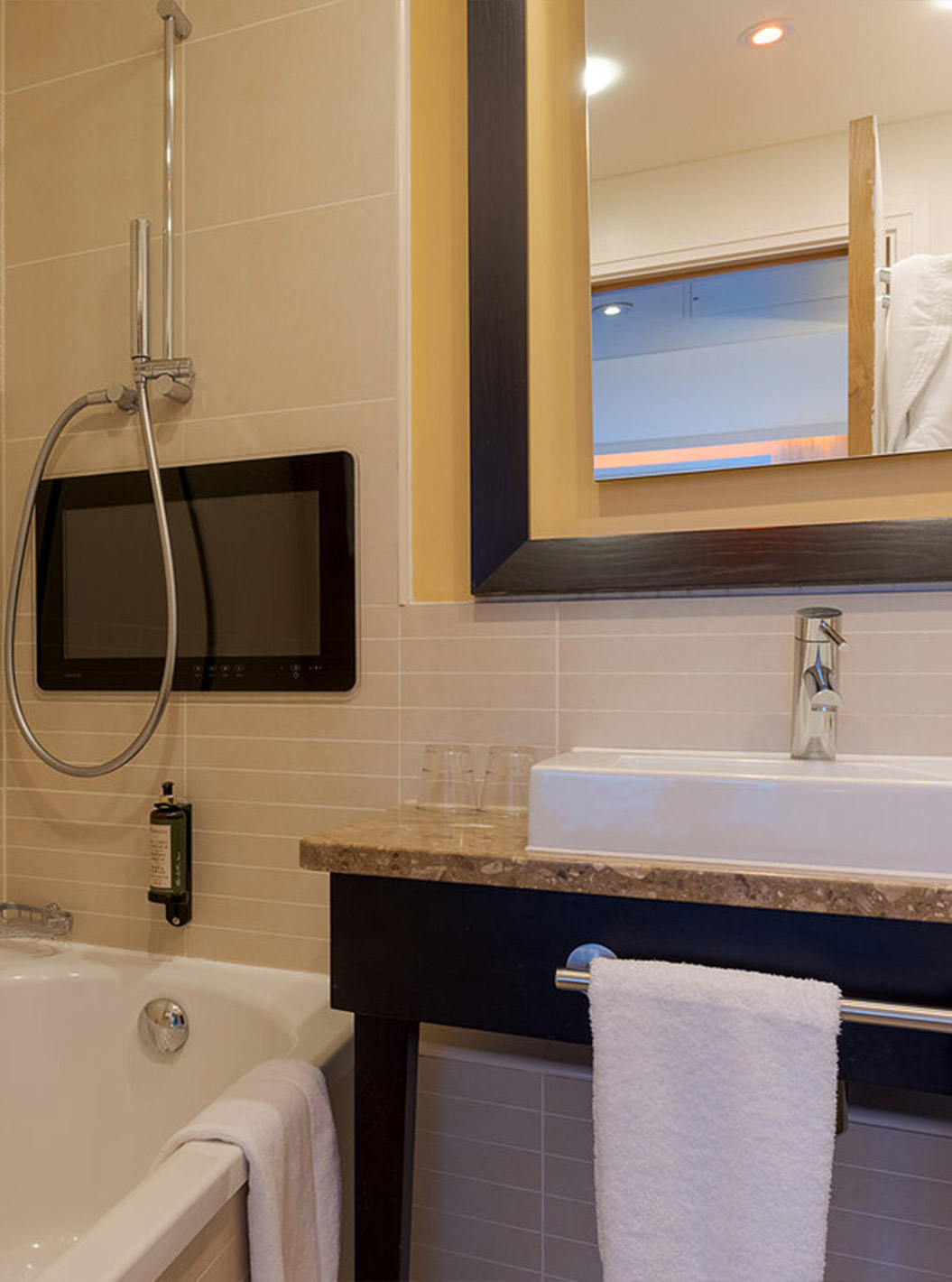 L’Executive One Bedroom Suite du Pestana Chelsea Bridge a salle de bain avec baignoire, lavabo, miroirs et sèche-cheveux