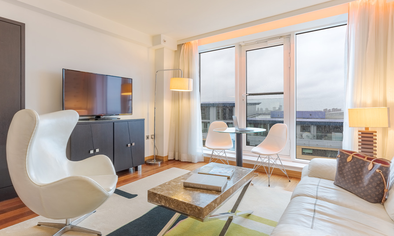 La Suite Exécutive 1 Chambre du Pestana Chelsea Bridge a un salon avec canapé, table basse, télévision et fenêtres