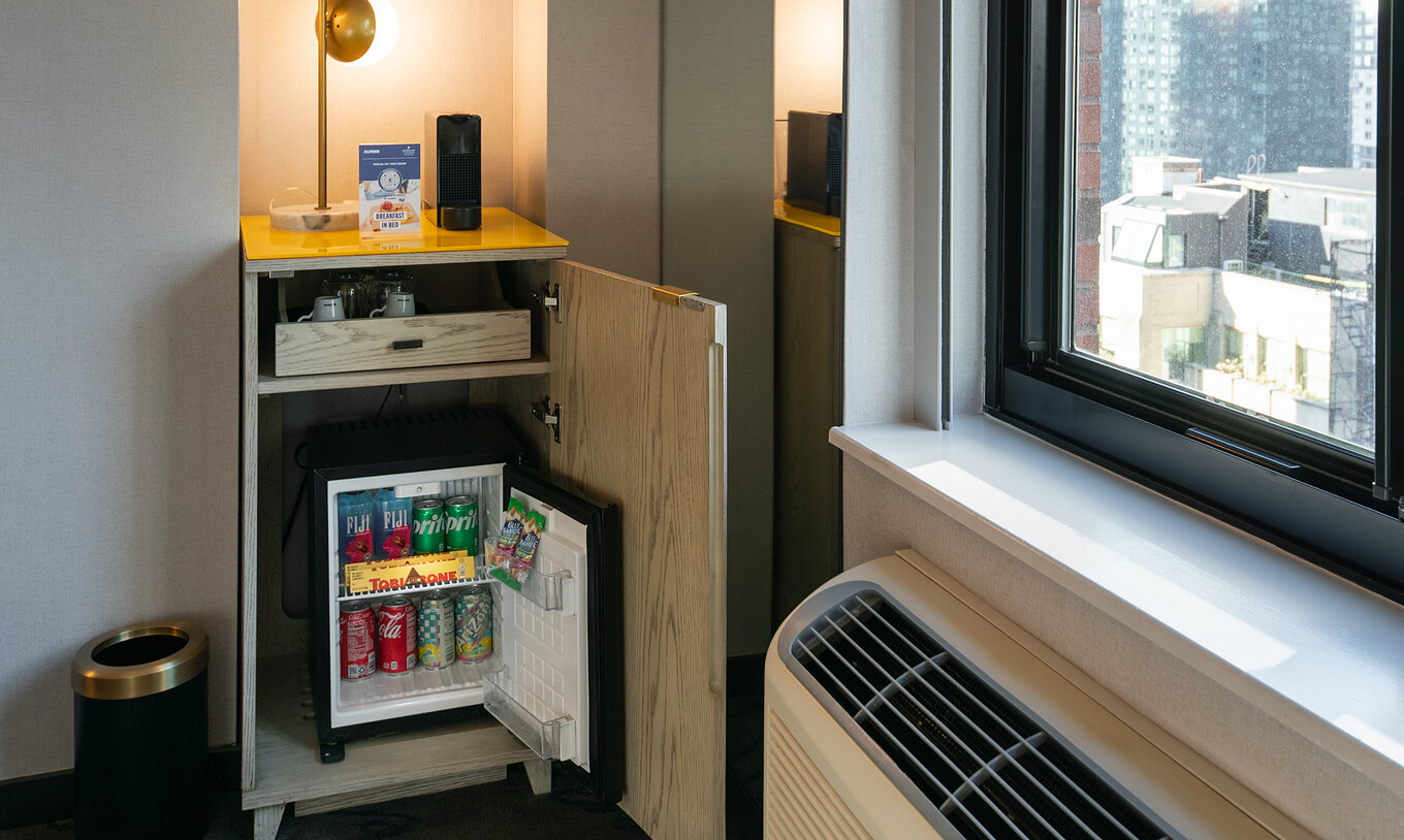 Le Deluxe King Room du Pestana CR7 Times Square a une armoire avec un minibar près de la fenêtre