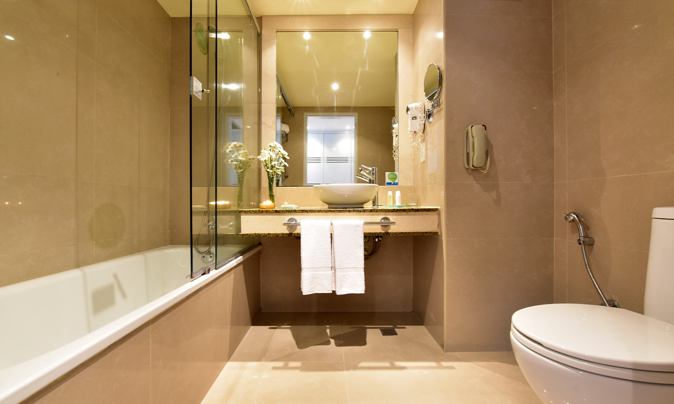 L’Executive King du Pestana Caracas a une salle de bain avec douche, lavabo avec miroir, sèche-cheveux et WC