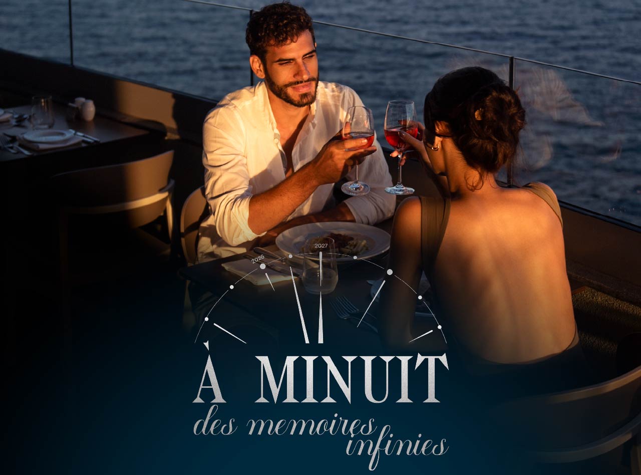 Couple levant des verres de vin lors d’un dîner au coucher du soleil face à la mer sur une terrasse élégante