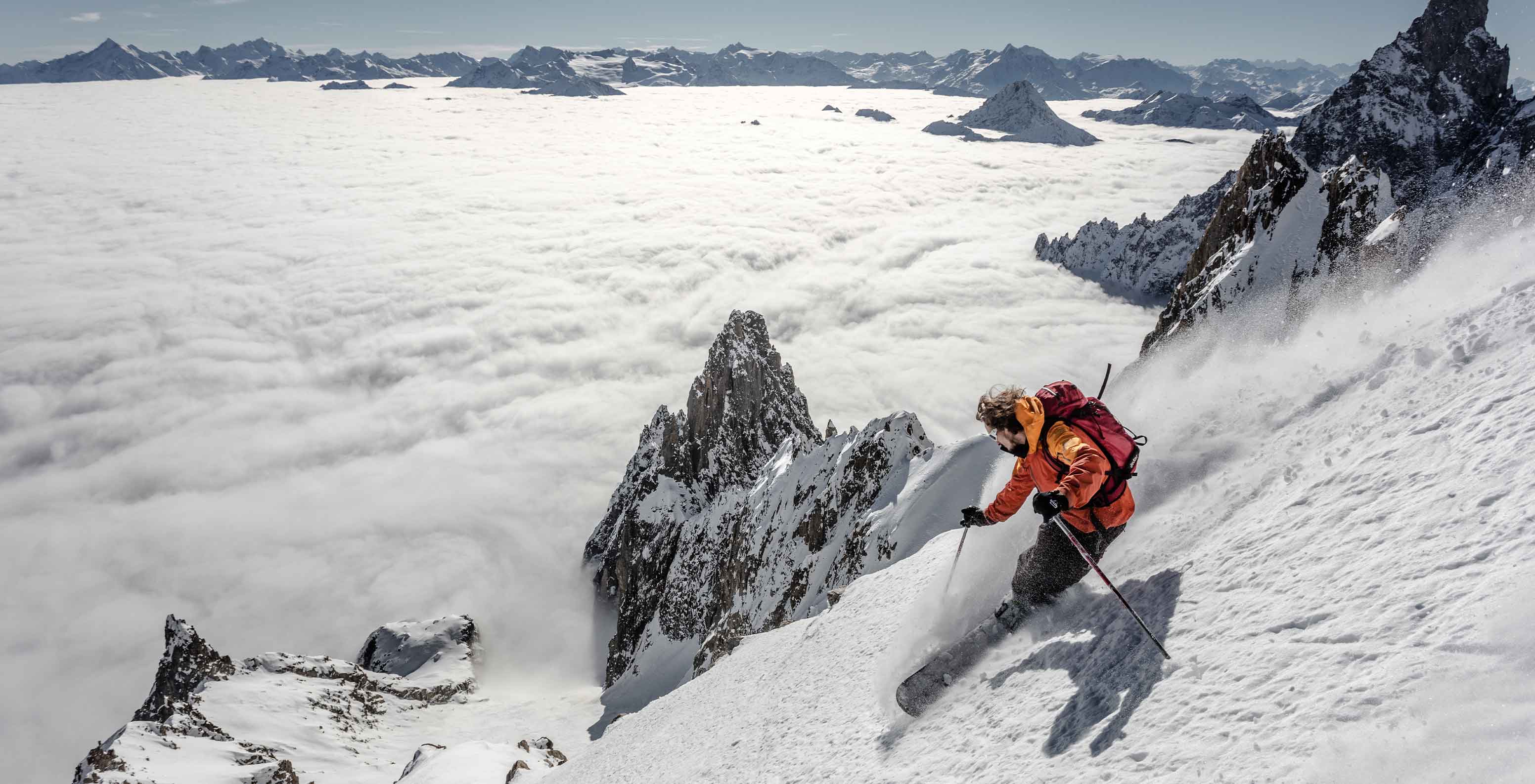 Pessoa a esquiar numa encosta coberta de neve com vista para montanhas e nuvens perto do Le Massif Courmayeur