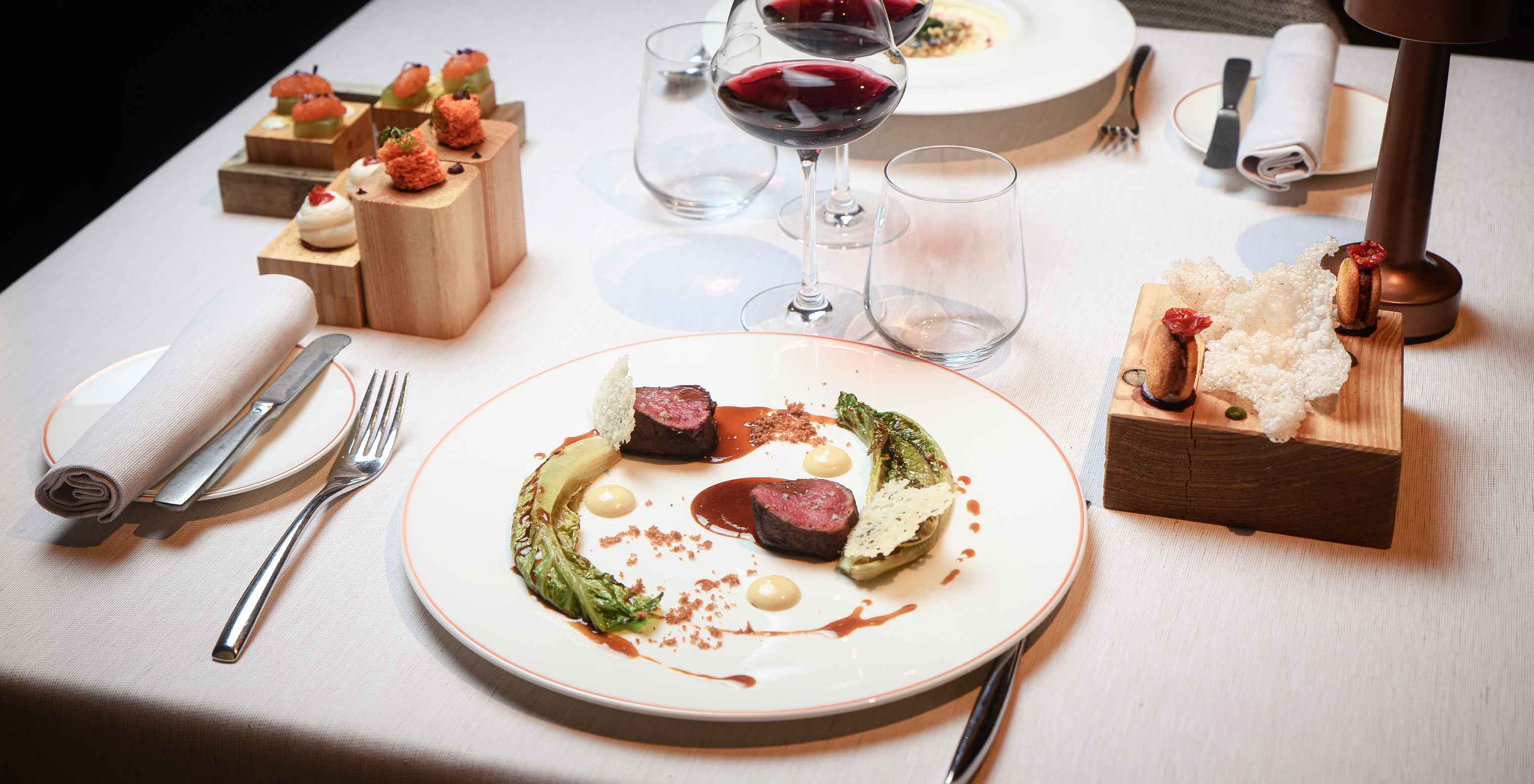 Restaurante do Le Massif Courmayeur, Hotel nos Alpes Italianos em Courmayeur para fazer ski, mesa posta com pratos gourmet e copos de vinho tinto