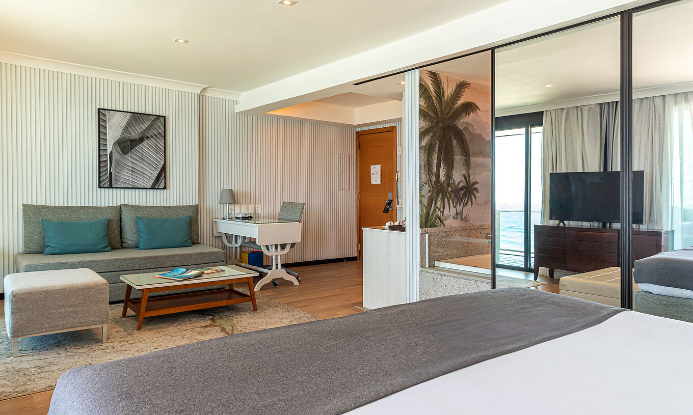 De Oceanische Suite van Pestana Rio Atlântica heeft moderne kamer met bed, bank, tafel en tv.