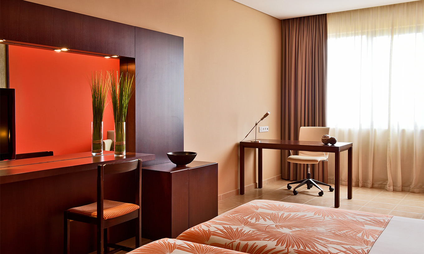 De Classic Sea View kamer van Pestana Tropico heeft een bureau met lamp en stoel, bed en spiegel