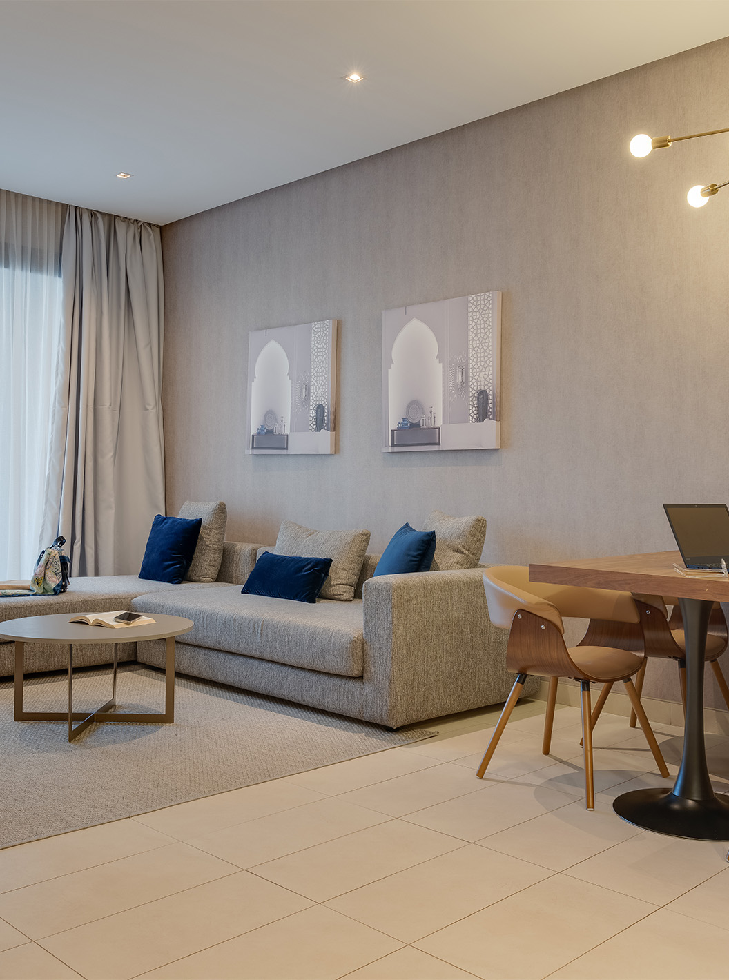 De Premium Familiale Superior Suite van Pestana Casablanca heeft een grote grijze bank met chaise longue bij het raam
