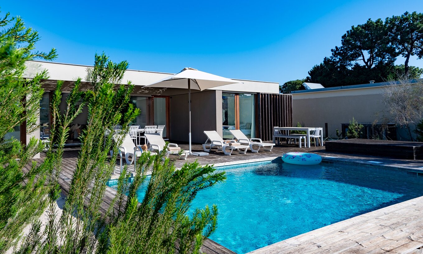 De Villas met 4 Slaapkamers van Pestana Tróia Eco Resort hebben verschillende ligstoelen en een parasol