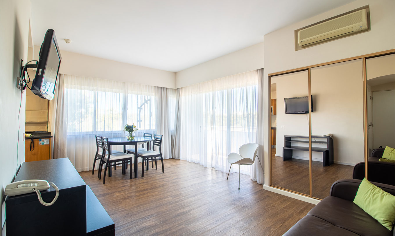 Het T1 Appartement Vista Jardim van Pestana Alvor Atlântico heeft een bank met televisie en een kast met spiegel