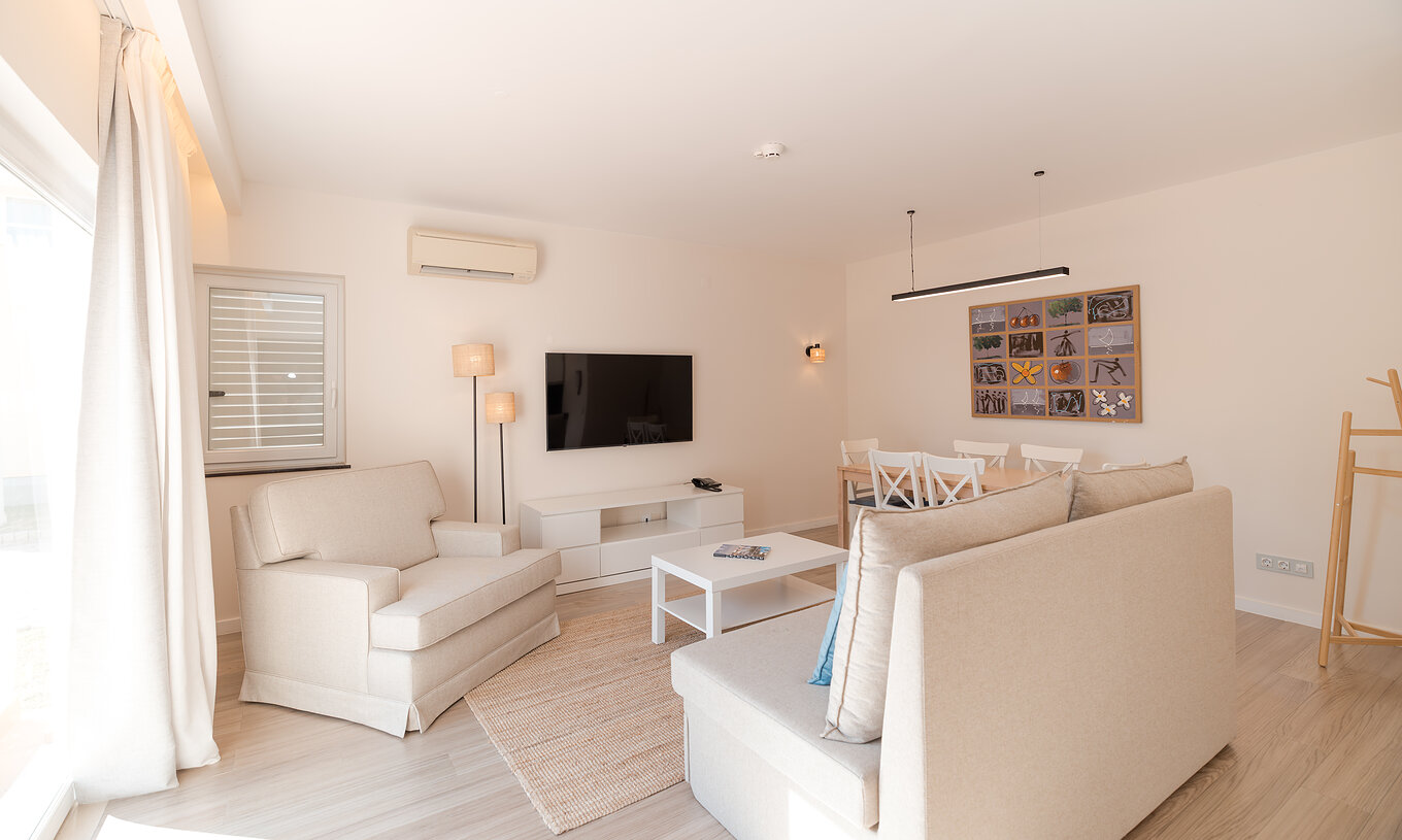 Villa 2 Slaapkamers Premium bij Pestana Alvor Beach Villas heeft woonkamer met beige banken, tv en airco