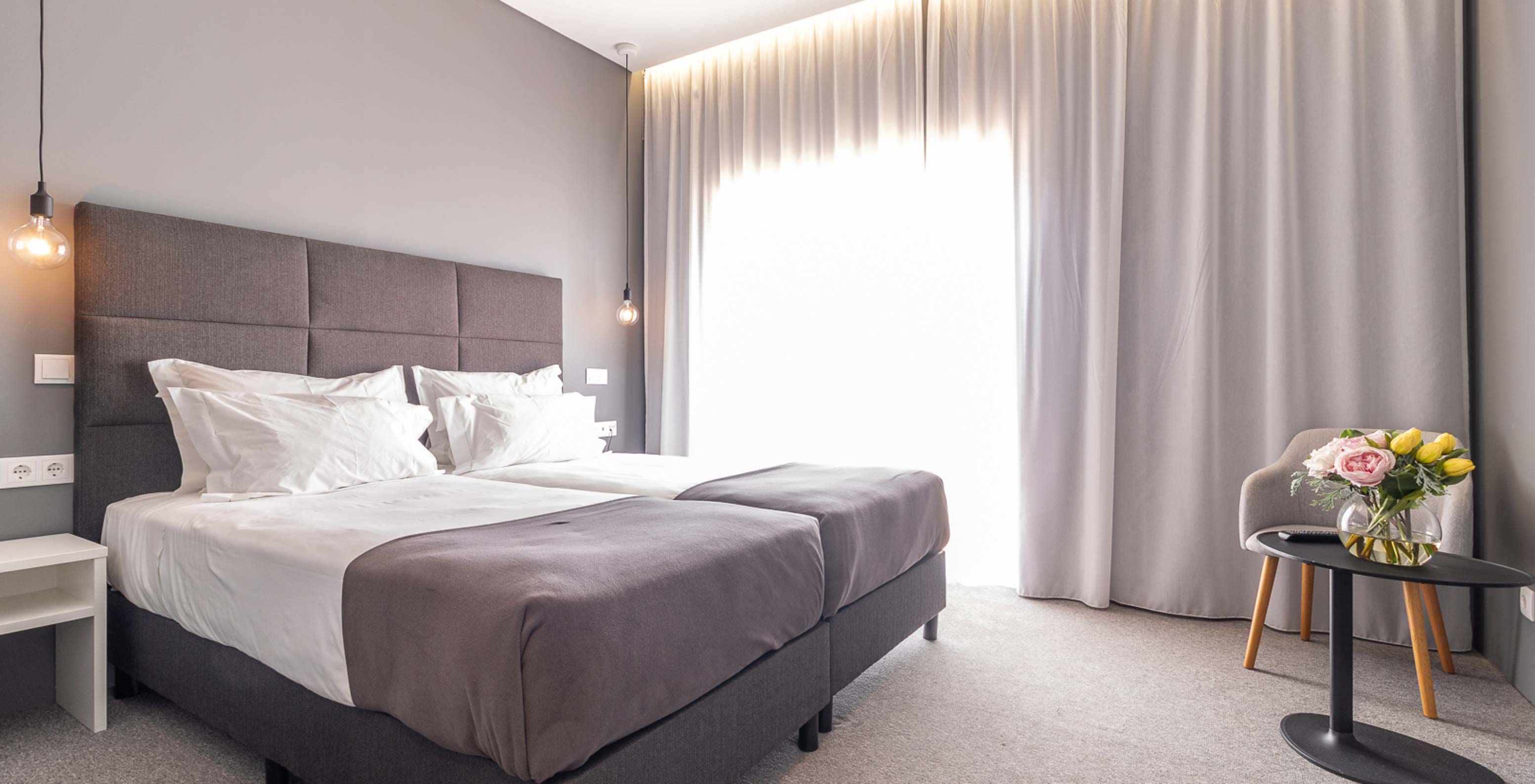 Klassieke kamer in Pestana Gramacho Residences met twee bedden, gordijnen en tafel met bloemen