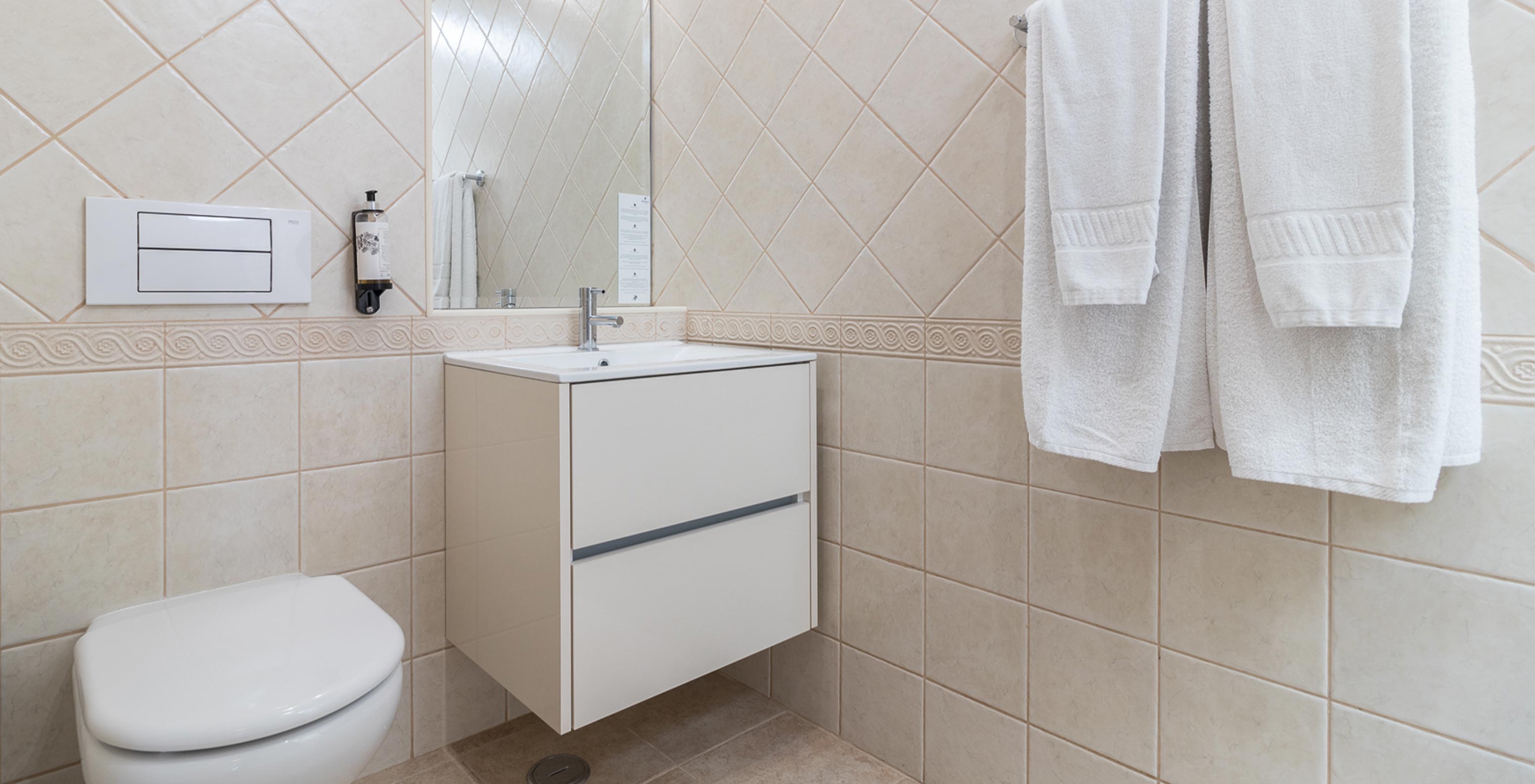 Het tweeslaapkamerappartement bij Pestana Gramacho heeft een elegante badkamer met witte handdoeken en zacht licht
