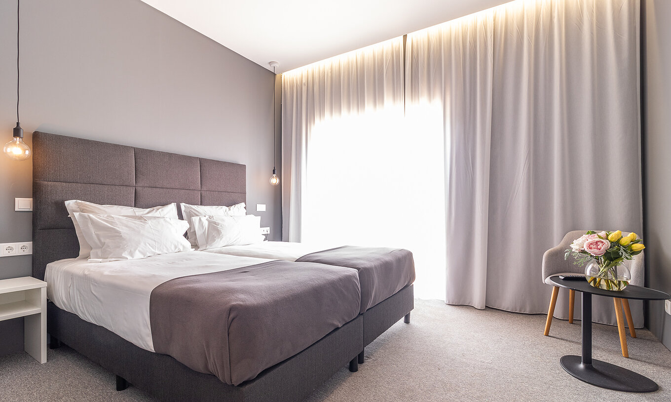 Klassieke kamer in Pestana Gramacho Residences met twee bedden, gordijnen en tafel met bloemen