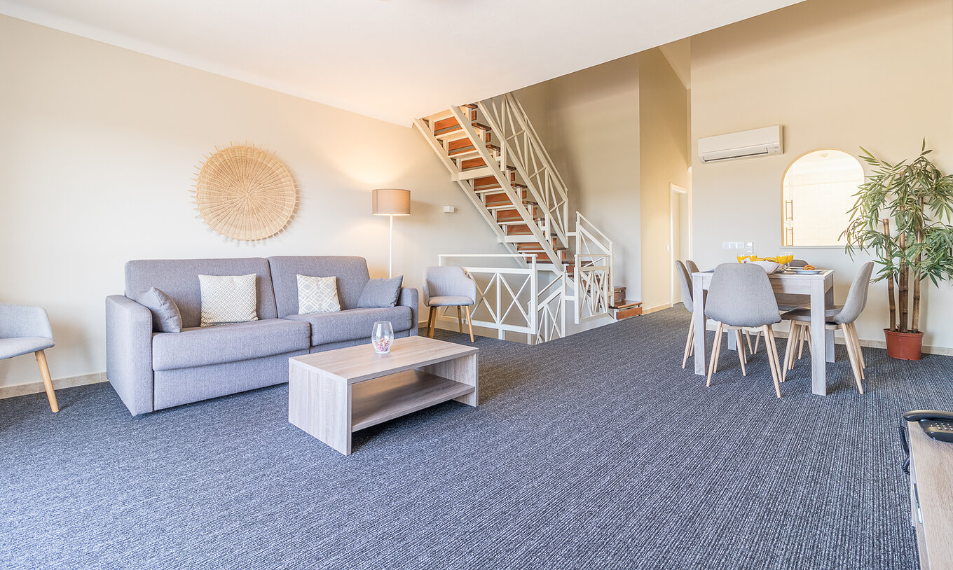 Het tweeslaapkamerappartement bij Pestana Gramacho heeft een salon met grijze sofa, tafel en trap achteraan