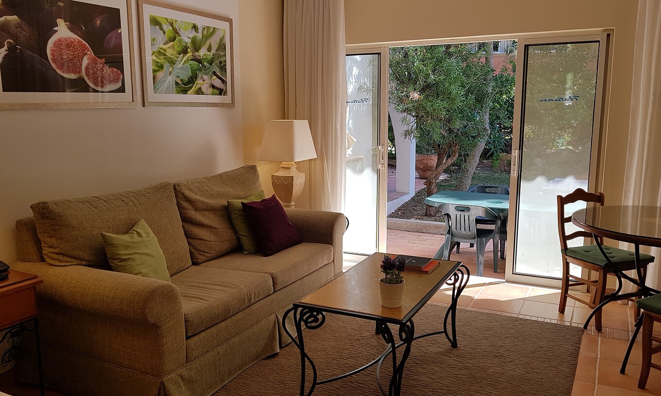 Het Studio van Pestana Palm Gardens heeft een woonkamer met bank en een raam dat toegang geeft tot de tuin