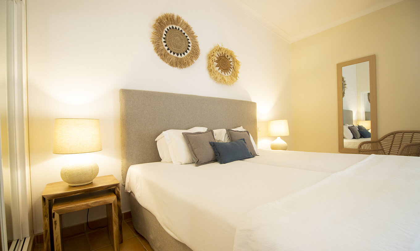 Het Appartement T2 Standard van Pestana Palm Gardens heeft een tweepersoonsbed met decoratieve kussens en schilderijen