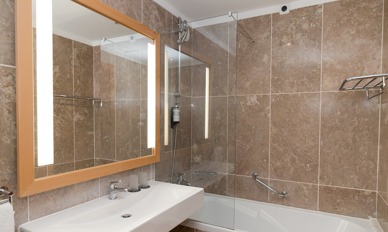 De Deluxe Zijzeezicht van Pestana Viking heeft een badkamer met wastafel, grote spiegel en bad met douche