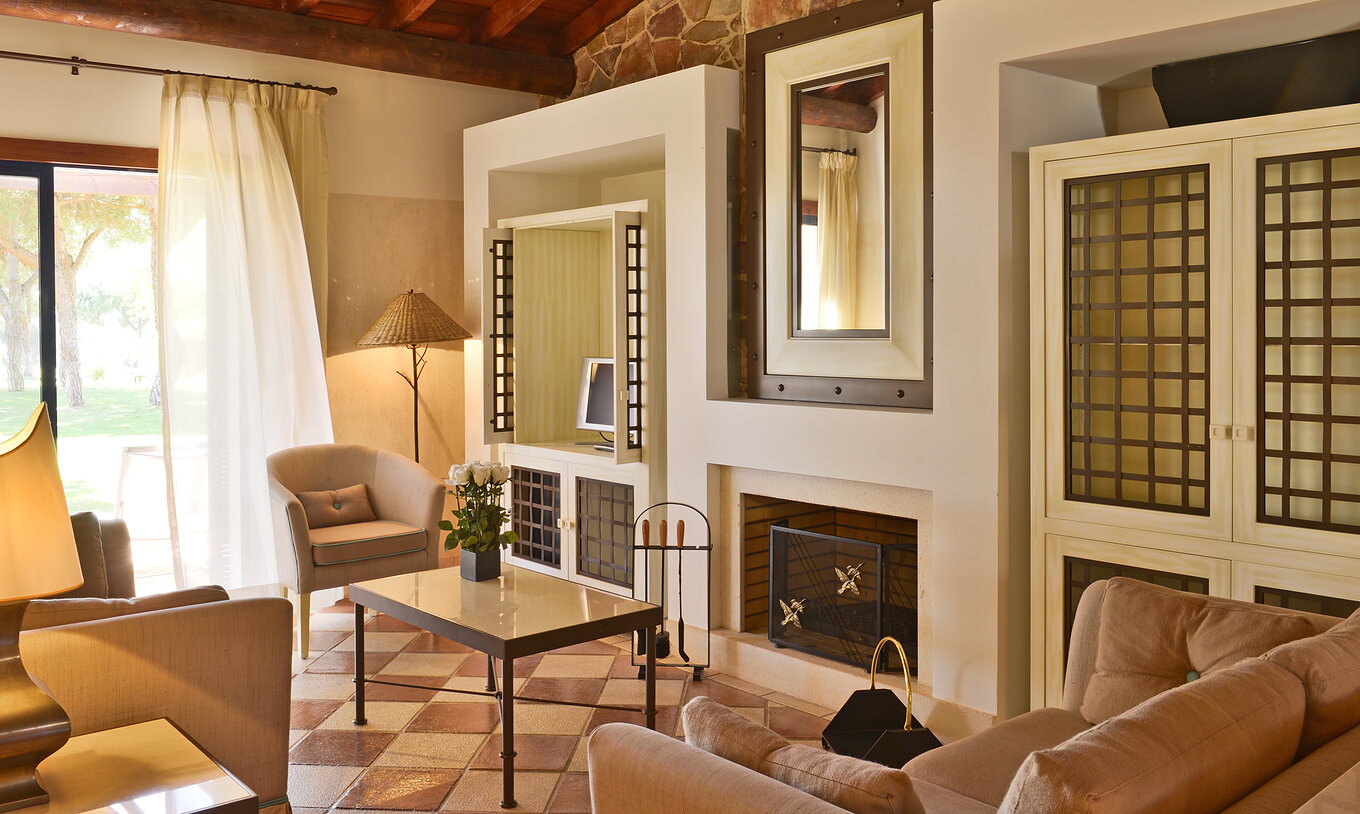 Suite uitzicht tuin Vila Sol van Pestana Vila Sol - Vilamoura heeft een woonkamer met sofa's, salontafel, open haard en raam