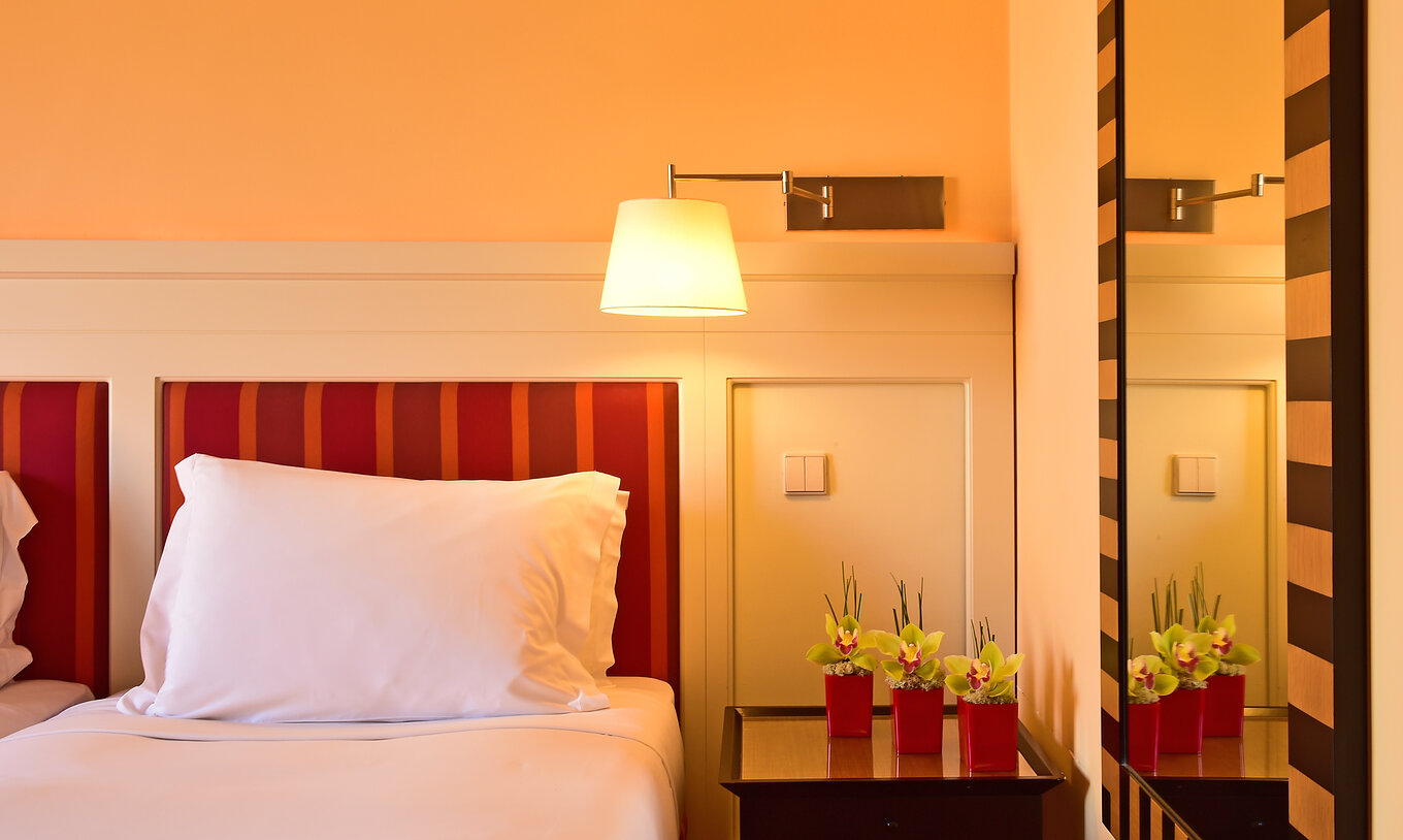 De Klassieke Tweepersoonskamer van Pestana Sintra Golf heeft een bed, een spiegel, een lamp en een nachtkastje met bloemen