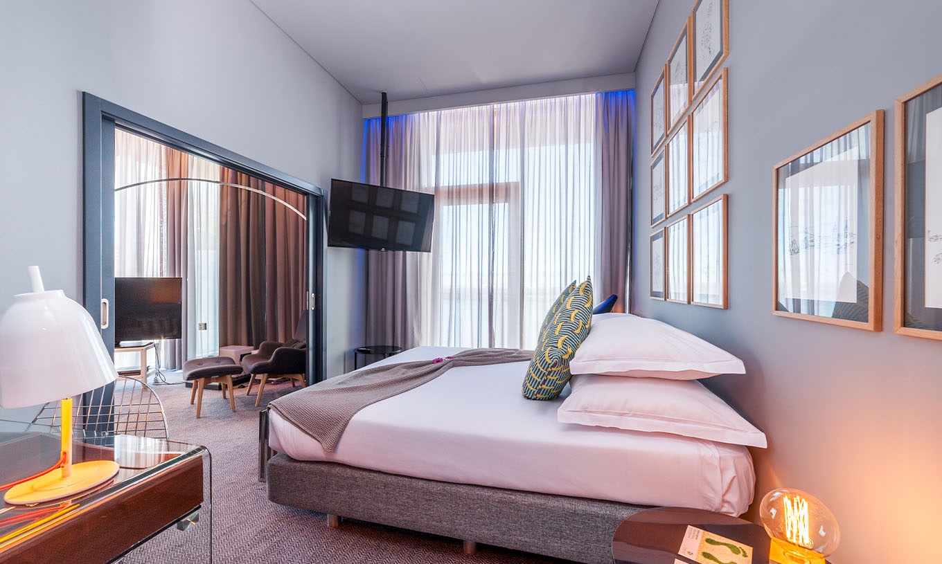 De CR7 Suite van Pestana CR7 Funchal heeft een slaapkamer met een tweepersoonsbed, een wandtelevisie en een raam