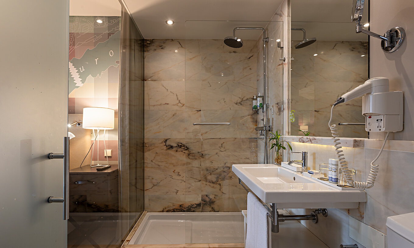 De Classic van het Pestana Vintage Porto heeft een badkamer met een wastafel en een douche omgeven door marmeren muren