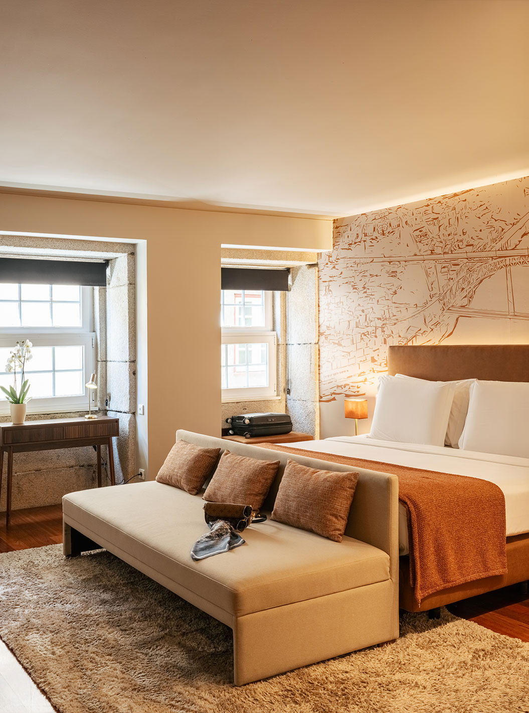 Erfgoedsuite van Pestana Vintage Porto met groot bed, bank en hoge ramen in een warme kamer met houten vloer