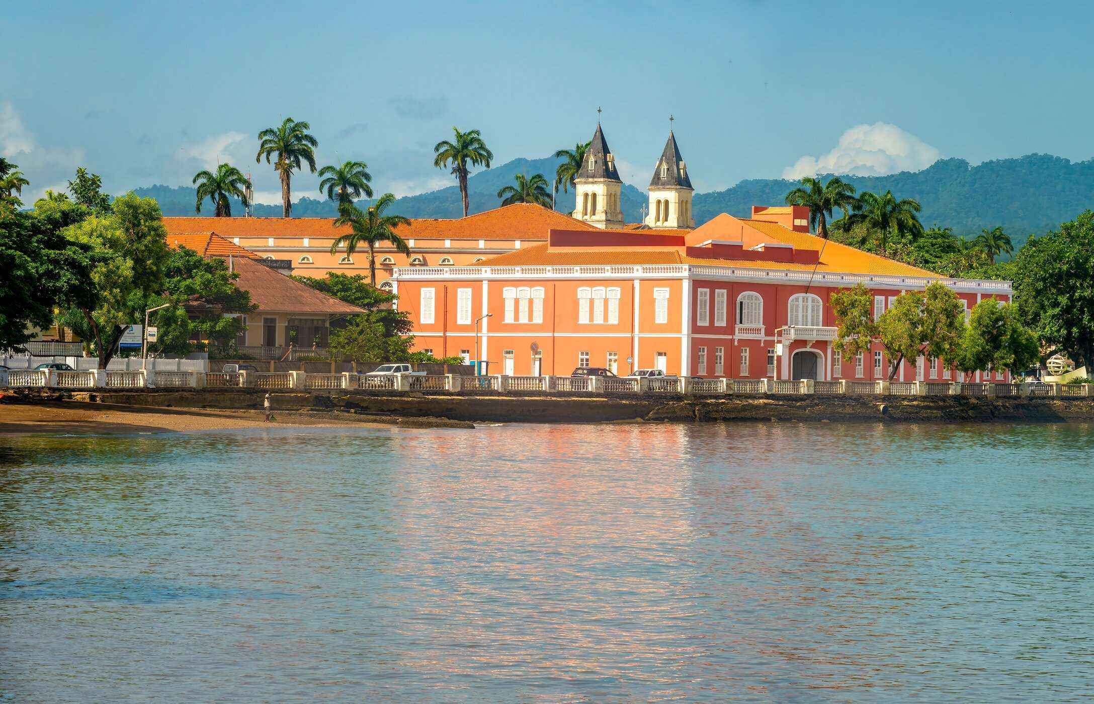 Panoramisch uitzicht op een historisch gebouw in São Tomé en Príncipe met oranje gevels, gelegen aan de zee.